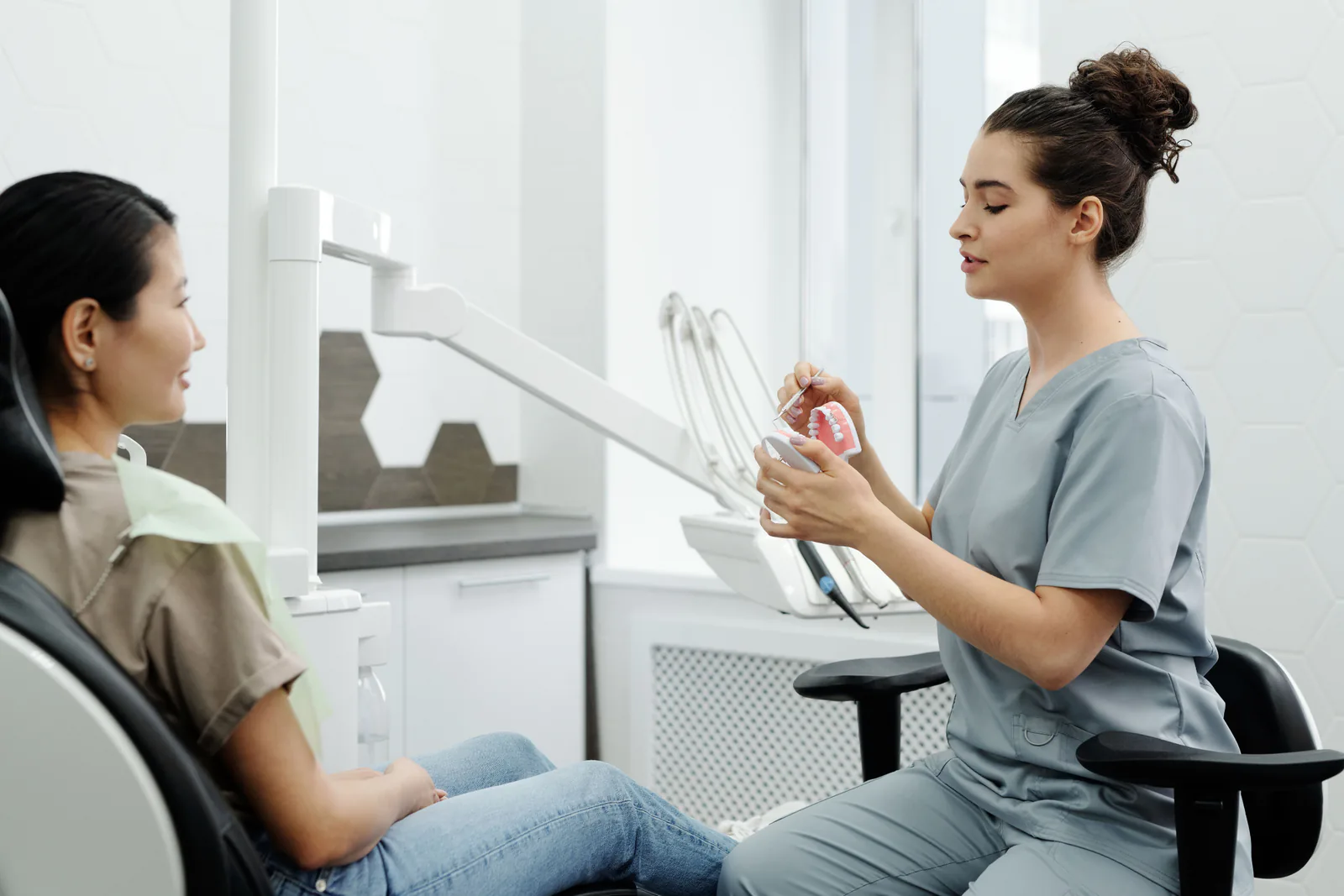 Profissional apresenta um modelo odontológico durante uma conversa clínica.
