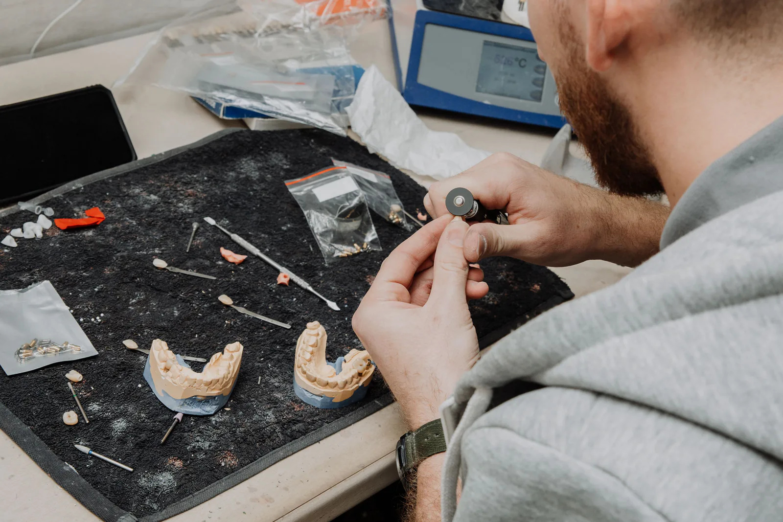 Técnico trabalha com um molde odontológico e instrumentos de precisão.
